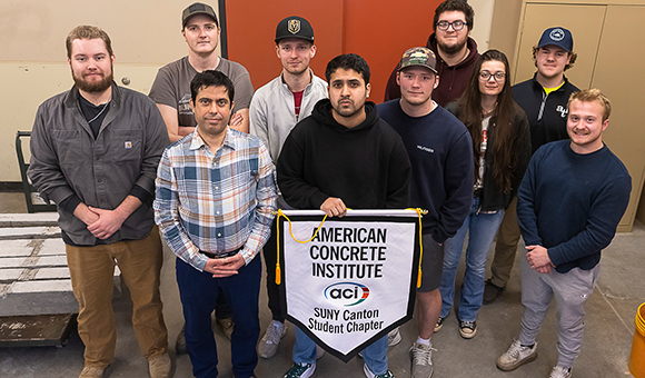 The American Concrete Institute student chapter holds up their banner.