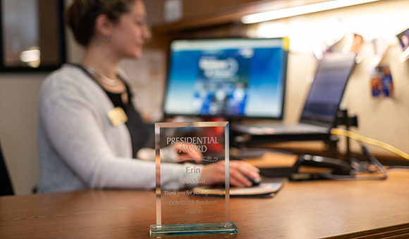 A Roosponder trophy sits on Erin Lassial's desk while she work at her computer.