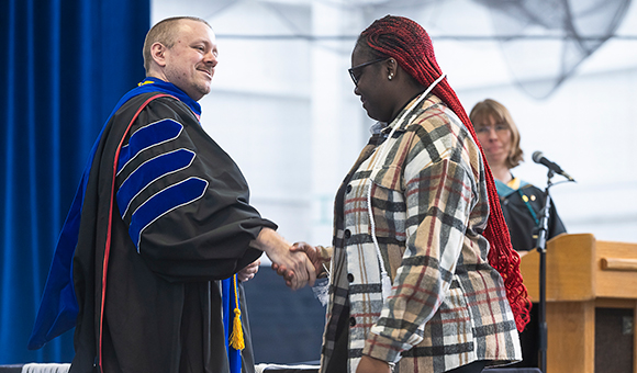Interim Dean Kirk Jones shakes hands with a student at Honors Convocation.
