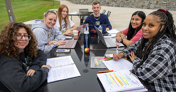 Students smiling and studying outside of Dana Hall.