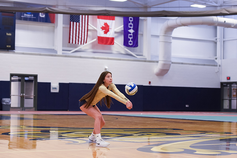 Tatum LaFrance sets a volleyball with the Iroquois flag in the background