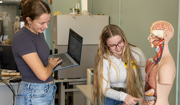 Asha Hanson and Lexi Blosenhauer work with an anatomy model in the tutoring lab.
