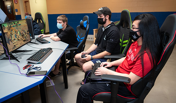 Andrew games with friends in the Esports Wing common area.
