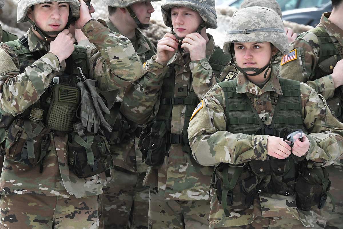 ROTC cadets in camouflage strap their helmets.