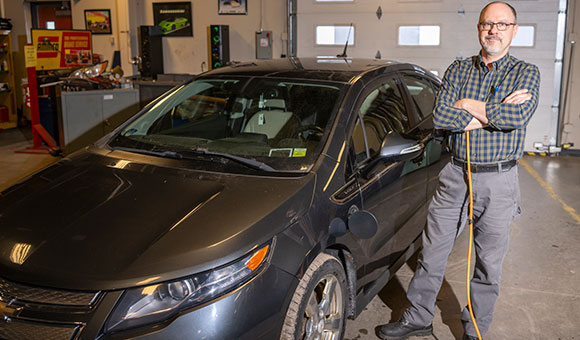 Brandon Baldwin stands next to a Chevy Volt.