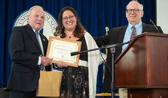Christina Leshko presented with award by Ronald O'Neill and President Szafran
