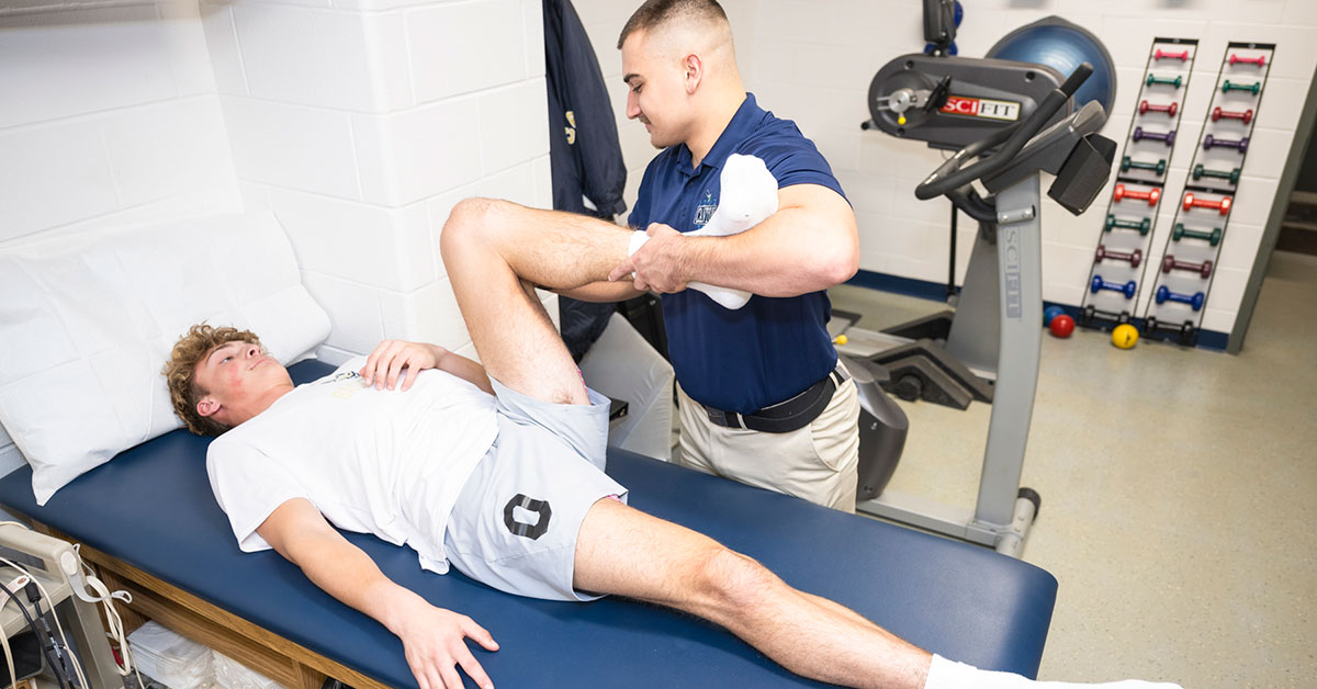 Connor Dickinson helps Finance major Nolan Sullivan stretch in the Physical Therapist Assistant lab.