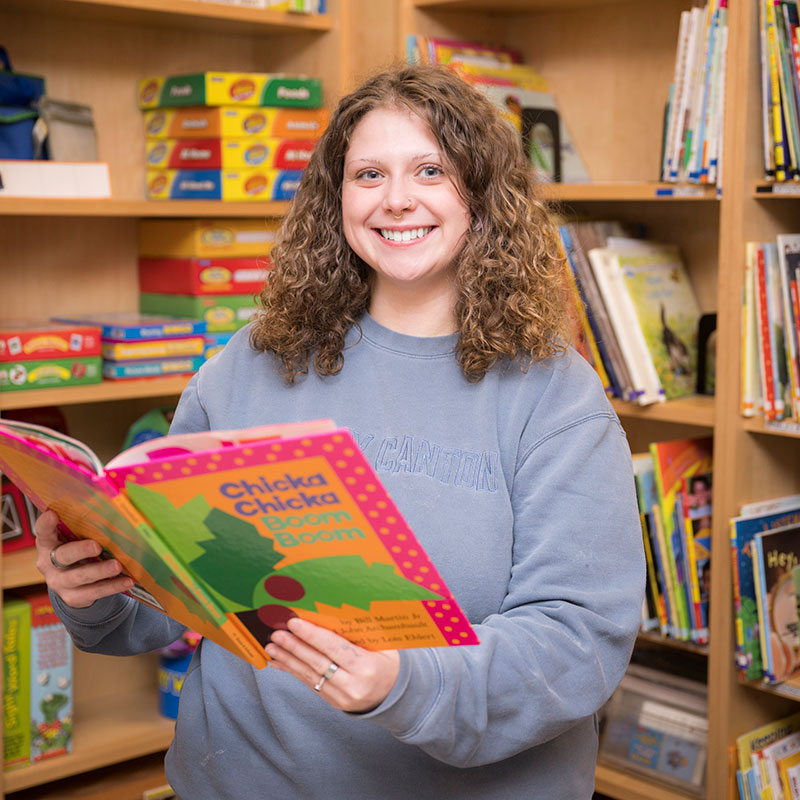 Emily Crossway holds the book Chick-A-Boom-Boom in the Early Childhood lab.