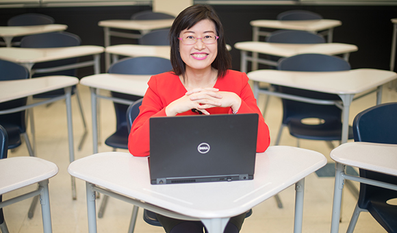 Eunju Yu sits in a classroom with a laptop.
