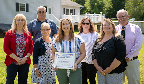 Family Child Care Training Program partners join Rebecca Peck as she displays her completion certificate.