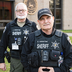 Jeffrey and Steven Forsythe stand outside the St. Lawrence County building in uniform.