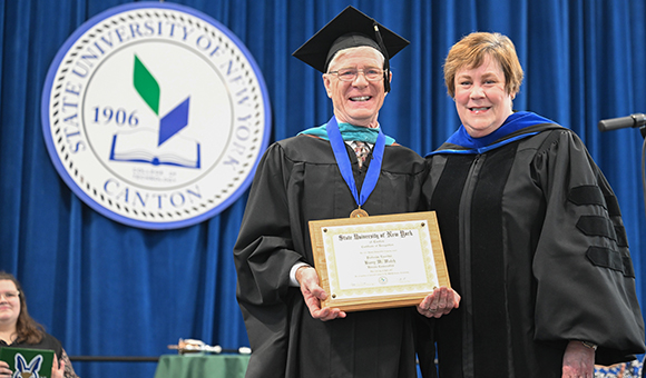 Provost De Cooke presents Barry Walch with a plaque at Honors Convocation.