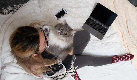 A student holds her cat, Po, while taking an online class