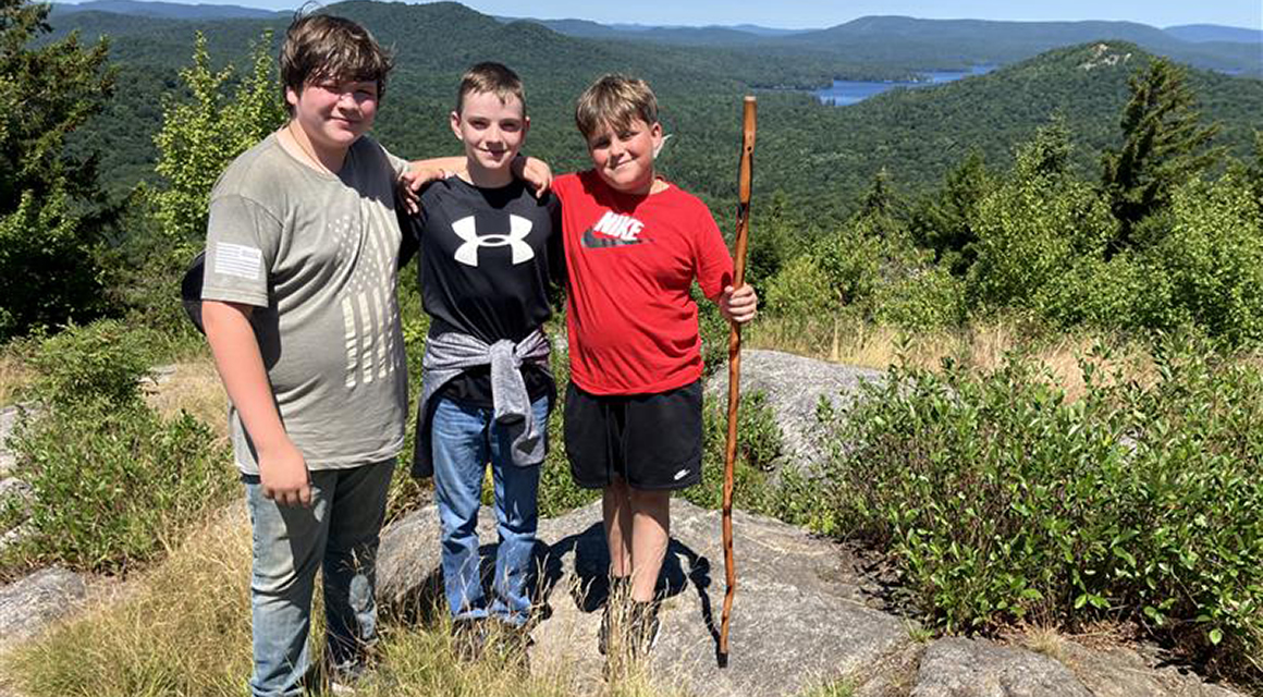 Three students pose at the top of Coney Mountain after a long hike.