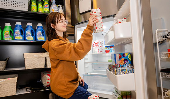 Elizabeth Carrera restocks the refrigerator in the college’s Renzi Food Pantry