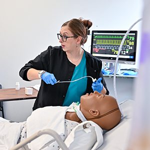 Samantha McCarthy demonstrates a medical procedure on a simulation mannekin.