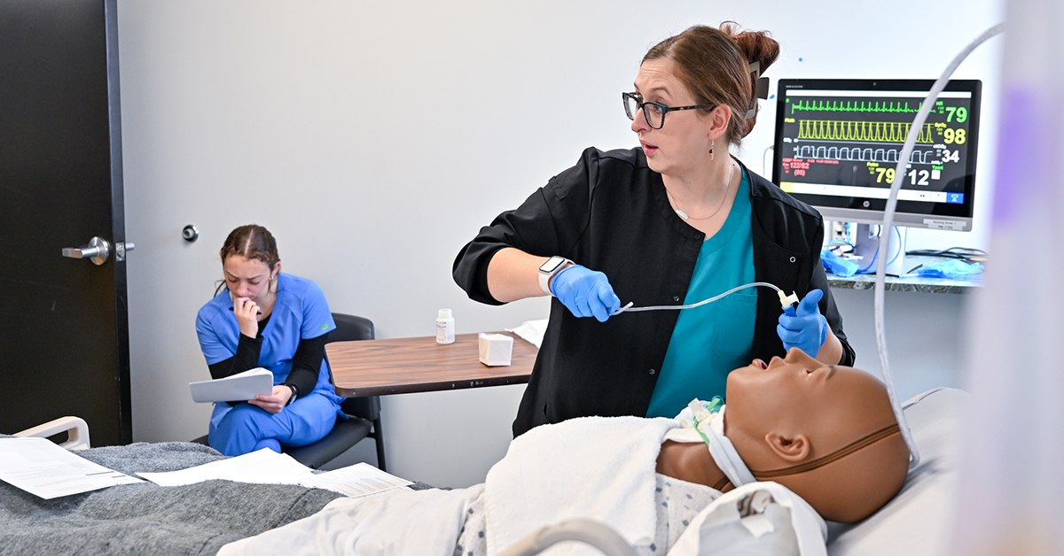 Samantha McCarthy demonstrates a medical procedure on a simulation mannekin.