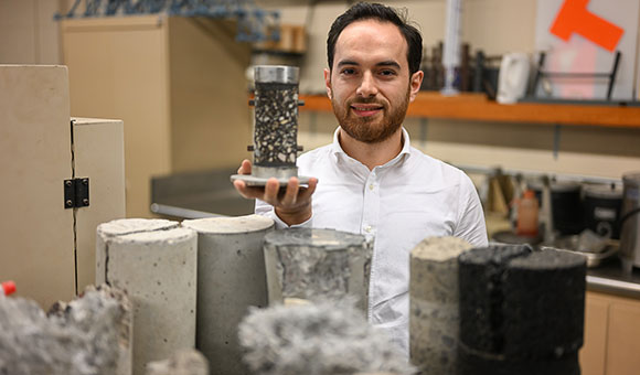 Aksel Seitllari holds an asphalt sample in the the Material Strength testing lab.