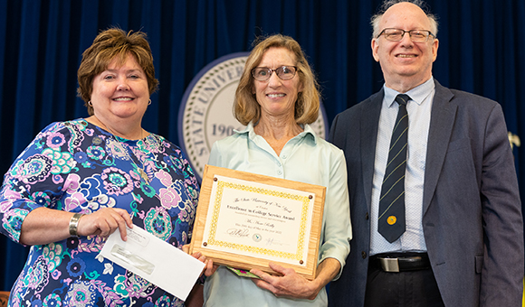 Anne Reilly accepts award from Jenn Stevenson and President Zvi Szafran