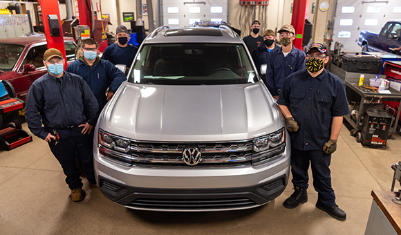 Students in SUNY Canton’s Automotive Technology lab stand with an Atlas donated by Volkswagen of America. The 2018 SUV is the newest car in the fleet of automotive test vehicles.