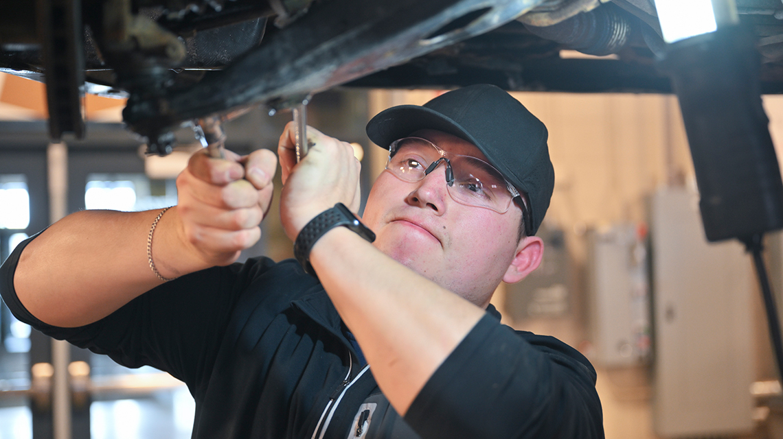 Byron Amaya removes a sway bar link on a Subaru in the Automotive Tech lab.