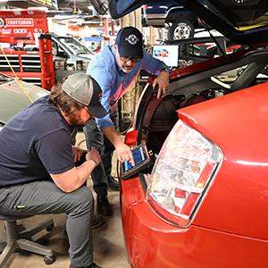 Two students perform a diagnostic scan of a Toyota Prius.