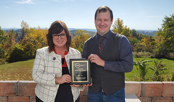 Dean of Students Courtney Bish and R.J. Thayer hold an award for online student engagement