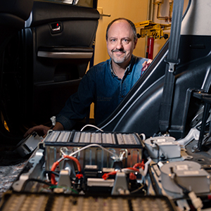 Brandon Baldwin stands behind a car engine.