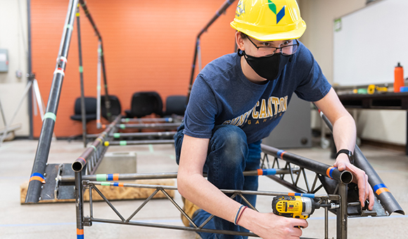 Benjamin York fastens a connection on the college’s steel bridge.