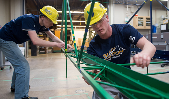 Students building a steel bridge.