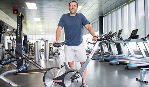 Bryan Parker stands with an exercise bike in the Fitness Center.