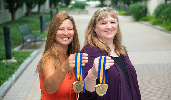 Renee Campbell and Kellie Harris hold out their Chancellor's Award medallions.