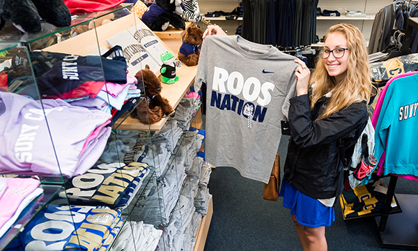 A student holds up a Roos Nation t-shirt in the Campus Store.