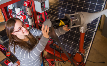 A student attaches a blade to a wind turbine.