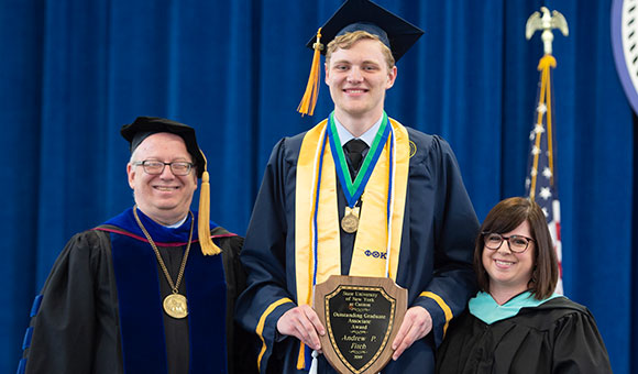 SUNY Canton graduate Andrew Fitch on stage with Zvi Szafran and Courtney Bish.