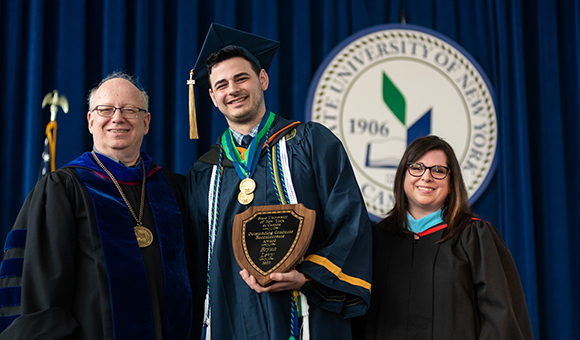 Bryan Levy receives the Outstanding Graduate Award from President Szafran and Vice President Courtney Bish.