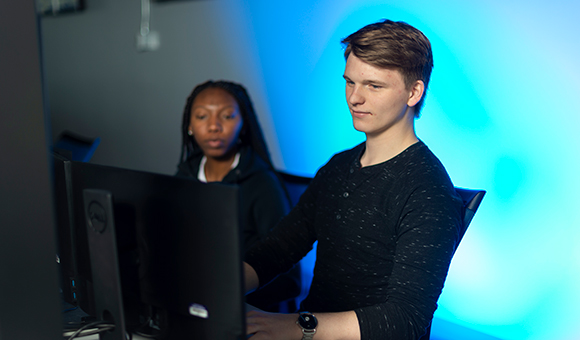 Two students work at a computer in the Cybersecurity lab.
