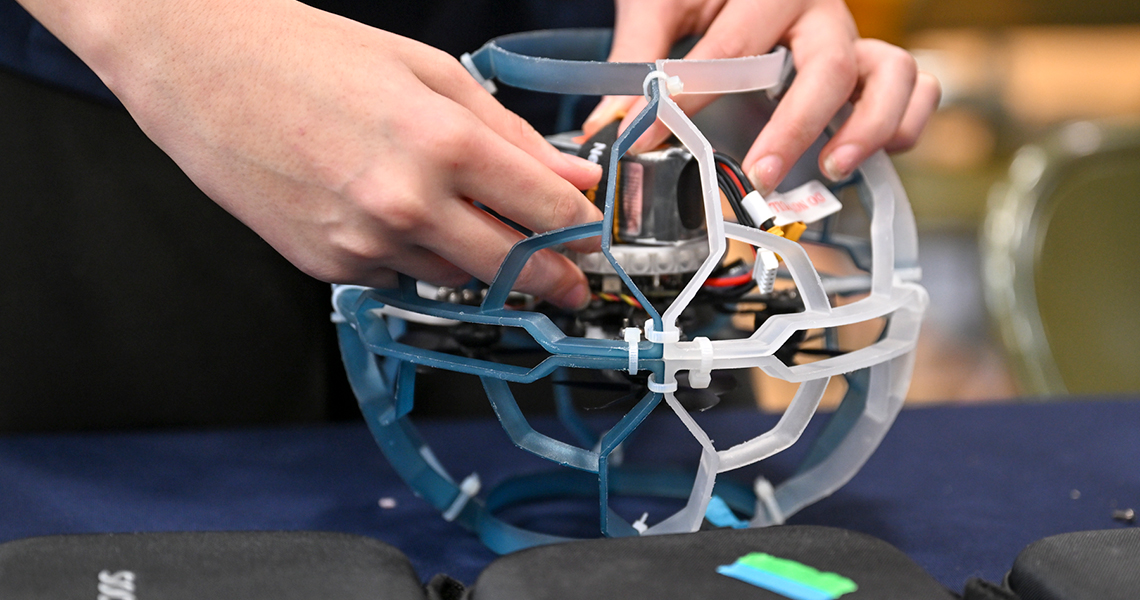 Close-up view of a student working to repair a damaged drone.