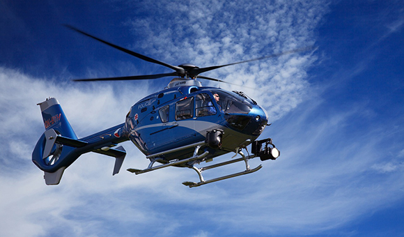 An emergency helicopter flies through a blue sky.