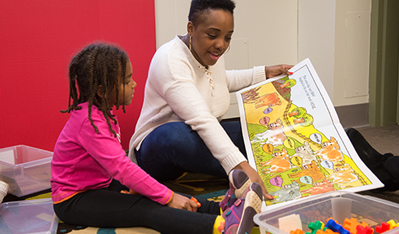 A student works with a toddler on reading activities