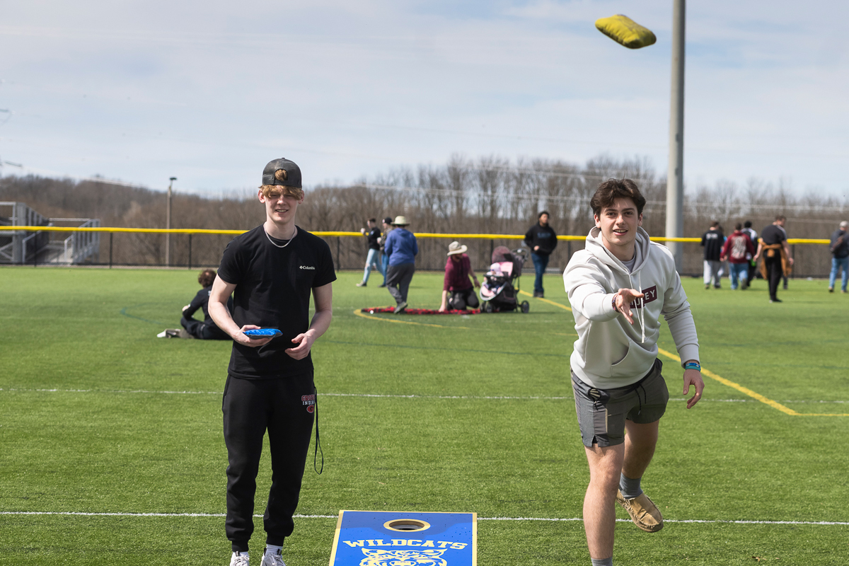Two students toss bean bags during a friendly game of cornhole.