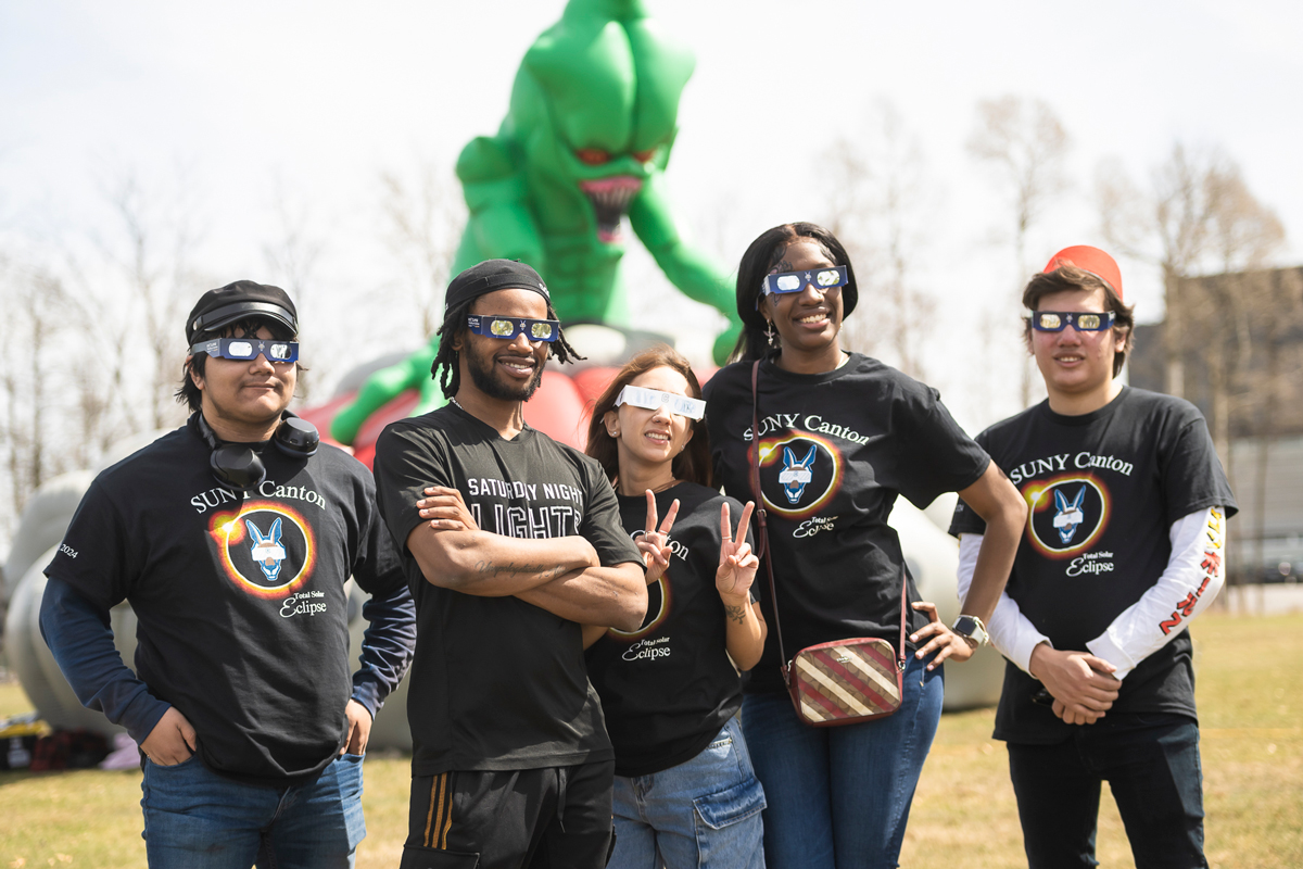 Students pose with eclipse glasses outside the laser tag blowup tent.