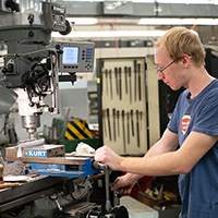 A student uses a drill press in the mechanical engineering lab.