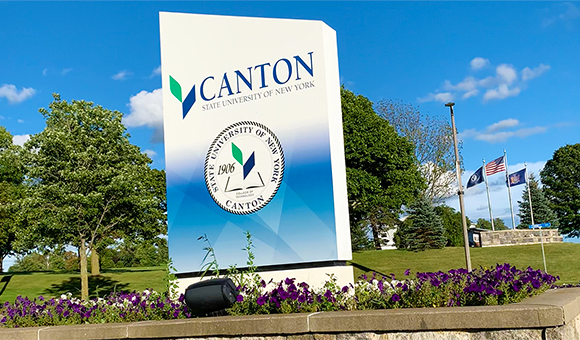 SUNY Canton entrance sign with flags in background