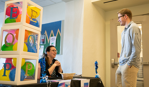 EOP Counselor Jessica Barstow speaks with Ryan Duester at a table to collect donations for Ukraine.