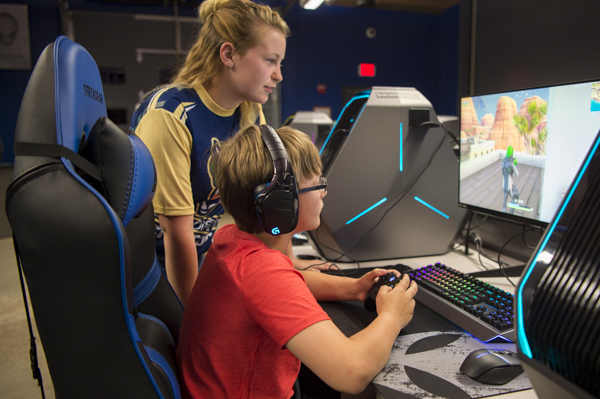 A SUNY Canton Esports player helps a young gamer.