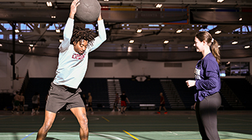 Ray Lopez and Natalie Baxter demonstrate medicine ball exercises in the Roos House as part of their Strength and Conditioning final.