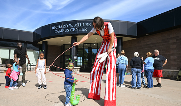 A clown on stilts greets families outside of Miller Campus Center during Family Weekend.