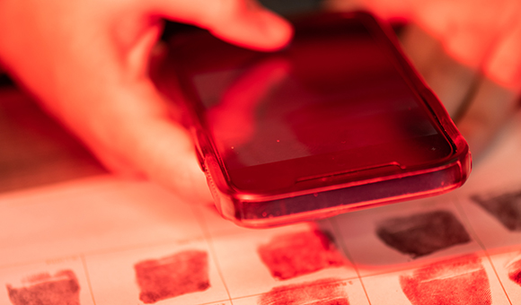 A student photographs fingerprints with a cell phone.