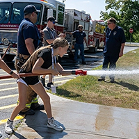 A camper sprays a fire hose outside Dana Hall.